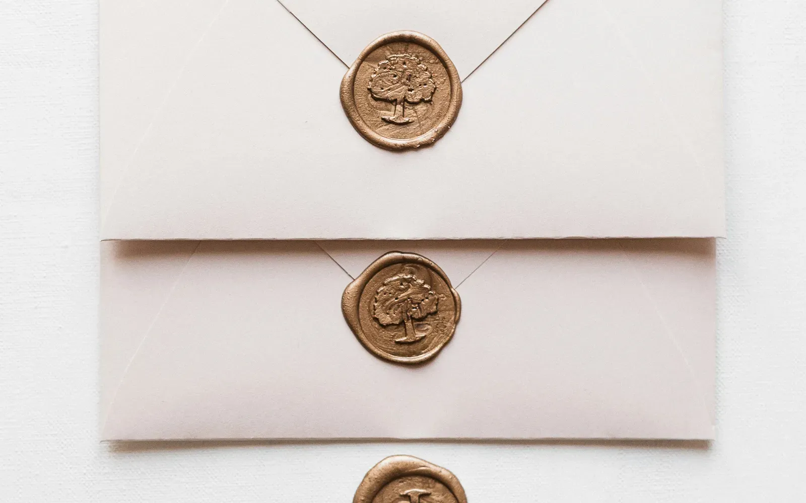 Drei elegante weiße Briefumschläge mit goldenen Wachssiegeln