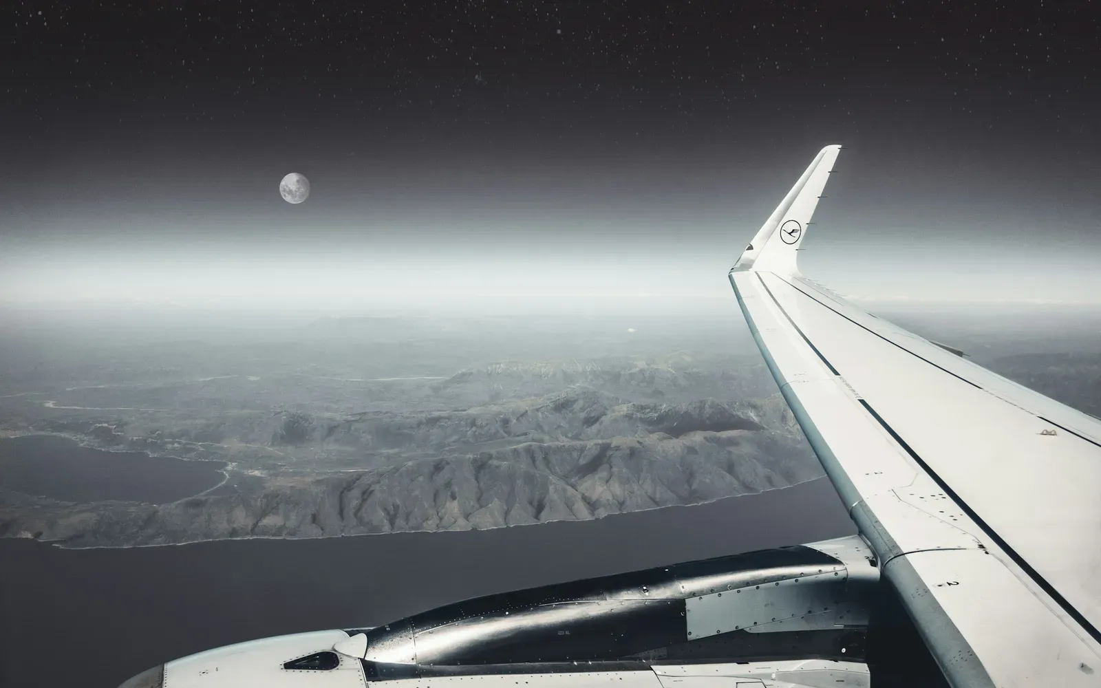 Blick aus dem Flugzeugfenster auf Tragfläche, Mond und Küste bei Nacht – Sex in der Fernbeziehung