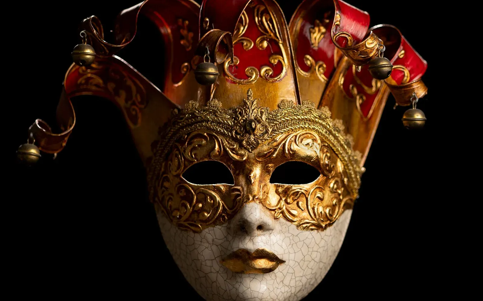 Venezianische Maske mit Narrenkappe vor schwarzem Hintergrund