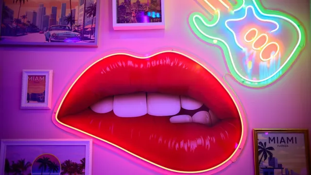 Leuchtende rote Neon-Lippen an einer pinken Wand – Sexting-Spiele für Paare und Chat-Partner