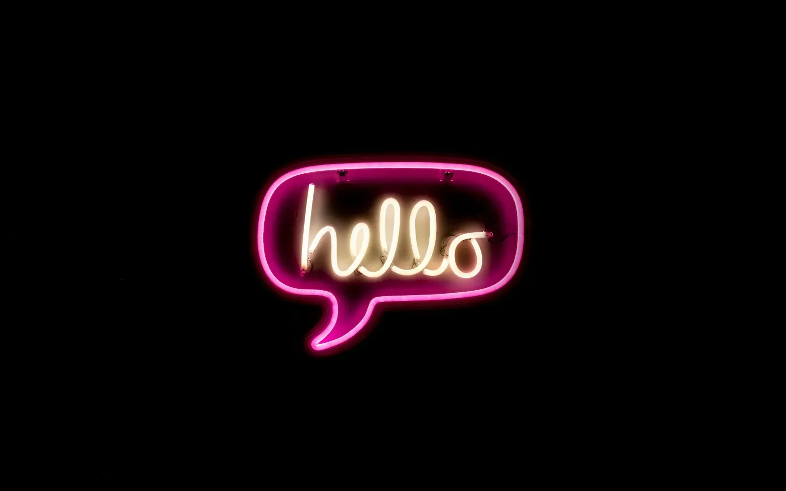 Pinke Neon-Sprechblase mit dem englischen Wort hello vor schwarzem Hintergrund – Dirty Talk auf Englisch