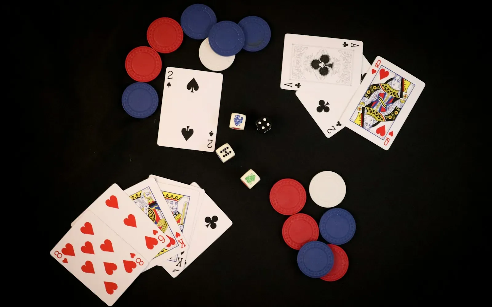 Spielkarten, Pokerchips und Würfel auf schwarzem Untergrund