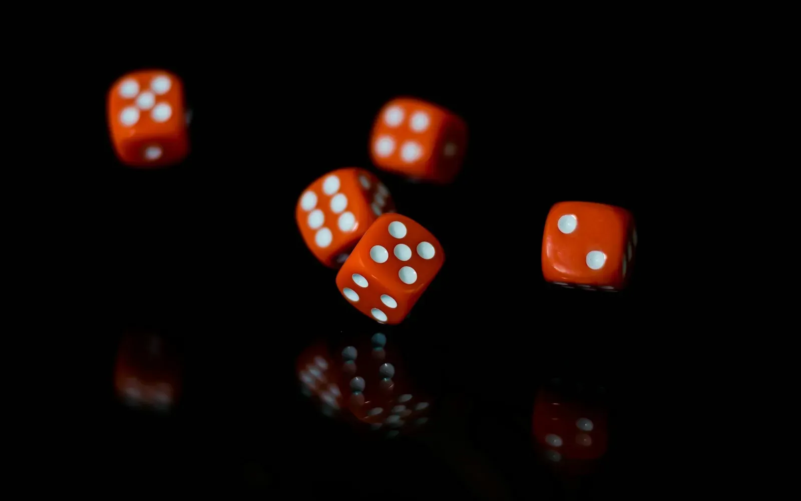 Rote Würfel mit weißen Augen fallen auf eine schwarze, spiegelnde Fläche